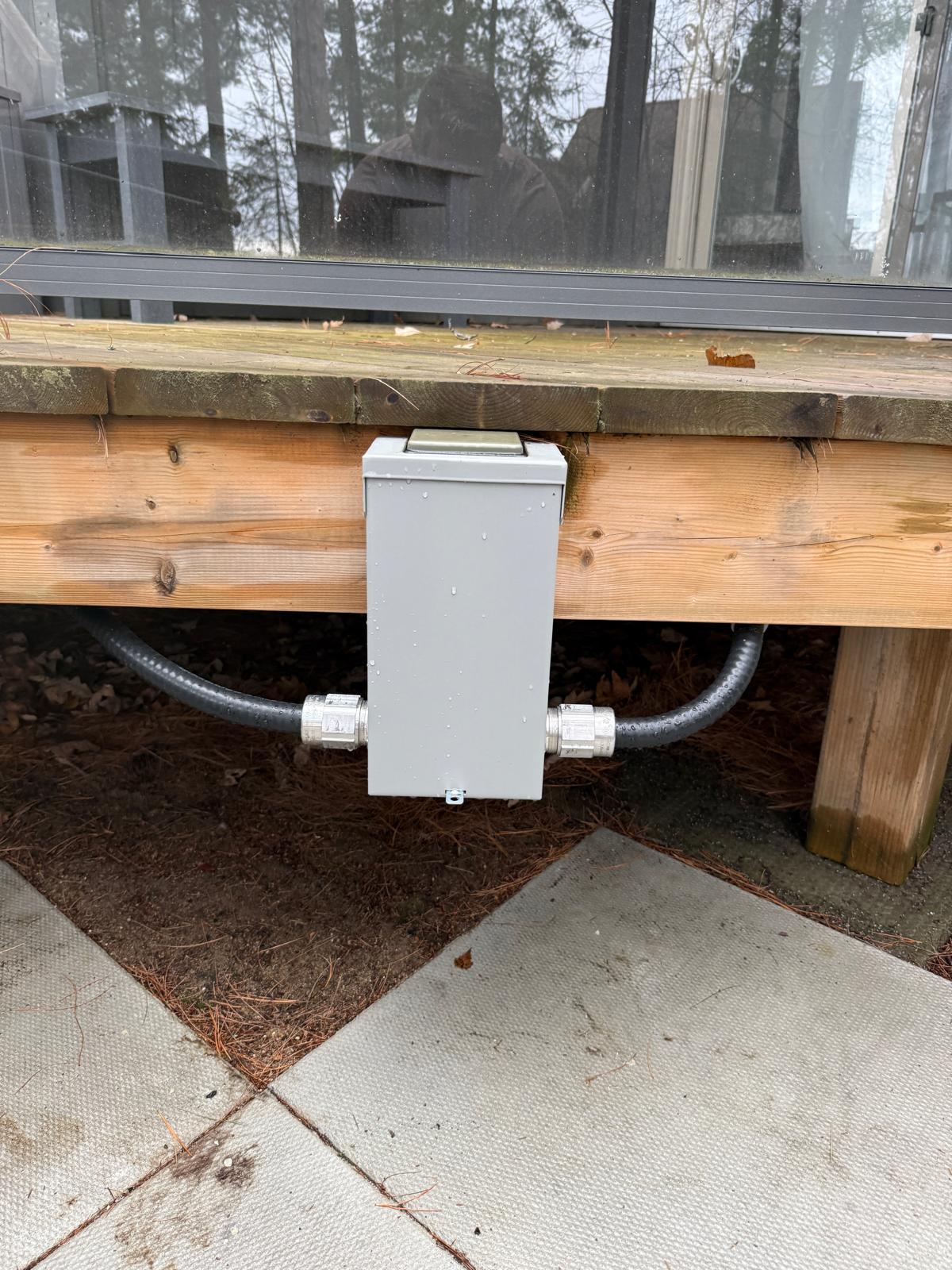 60A GFCI disconnect mounted under the deck rail — within sight of the tub, weatherproof, and out of the way. Liquidtight FMC in and out.
