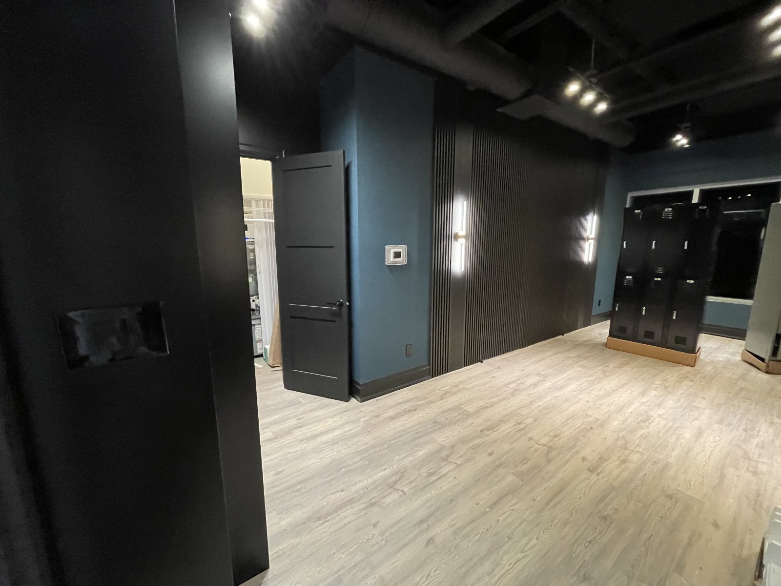 Entry corridor — track lighting, locker-bank power along the right wall, scene control at the entry.