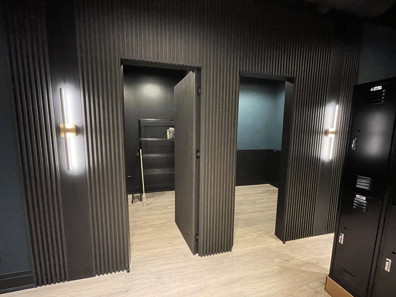 Private office pods — power and data feeds in each, brass linear sconces between fluted panels.